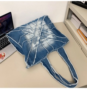 Close-up of blue denim patchwork tote bag with frayed edges and textured fabric details