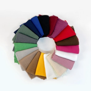 Macro view of textured linen scarves with natural fringed edges in various vibrant colors