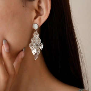 Close-up of a silver multi-layered hollow leaf tassel earring worn on a female model