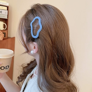 Close-up of blue denim textured wavy hair clip worn on side of brown wavy hair