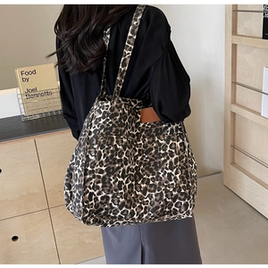 Macro detail of leopard print canvas fabric with brown leather patch on tote bag