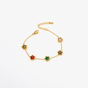 Detailed view of golden bracelet featuring colorful star-shaped emerald and zircon charms