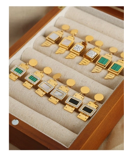 Detailed macro view of gold-plated titanium earrings with malachite and shell inlays