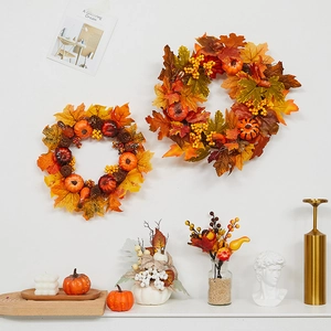 Autumn wreath with maple leaves, pumpkins and berries hanging on a white wall decor