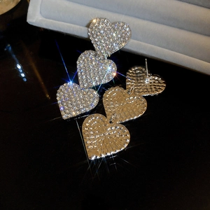 Detail of silver heart drop earrings with shimmering rhinestones on black mirror base