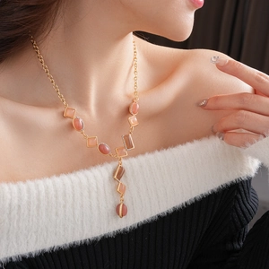 Close-up of vintage Y-shaped necklace with pink oval gemstones and sparkling rhinestones