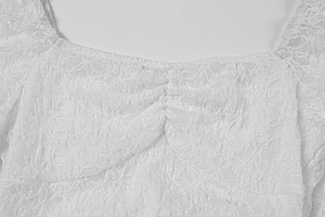 Détail de l'encolure carrée avec fronces et dentelle florale délicate en blanc