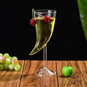 Detailed view of horn-shaped glass cocktail cup with garnish on dark wood surface
