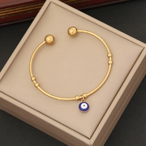 Detailed macro shot of a gold stainless steel open bangle with blue evil eye pendant