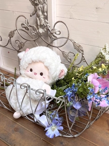 Close-up of soft white plush sheep backpack with cute expression on a rustic wood background