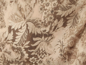 Close-up detail of vintage floral print fabric showing intricate beige and brown patterns