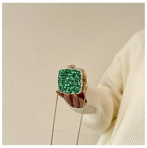 Macro shot of green sequined evening bag with golden metal frame and chain strap