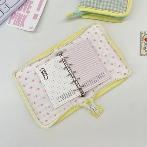 Detail of yellow zipper binder showing pink star lining and metallic loose-leaf rings