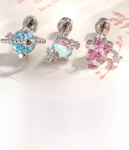 Macro detail of silver titanium steel earrings with pink star and blue planet designs