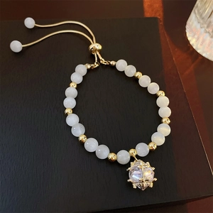 Detail eines Perlenarmbands aus Katzenaugen-Opal mit goldener Kette und Kristallanhänger
