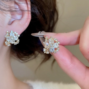 Detailed close-up of crystal flower stud earrings with shimmering gold settings on ear