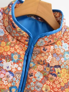 Detailed view of quilted floral jacket featuring retro print and blue contrast lining