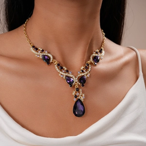 Close-up of vintage gold necklace with purple teardrop stones and pavé crystals