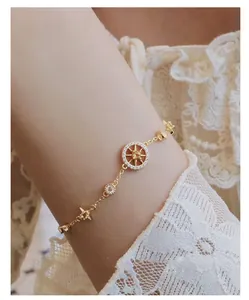 Detail of gold star compass bracelet with zircon pavé on female model wrist