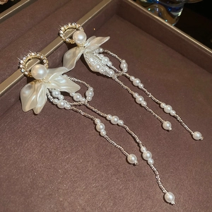 Detail of floral tassel earrings with pearls and rhinestones on a brown tray