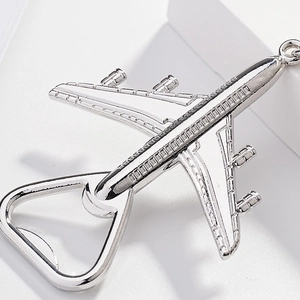 Macro detail of silver airplane bottle opener keychain on a white geometric background