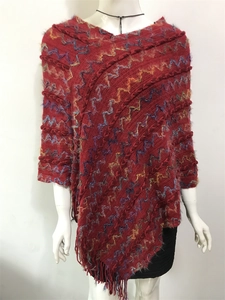 Gros plan sur un châle en tricot rouge ethnique avec motifs ondulés et détails à franges
