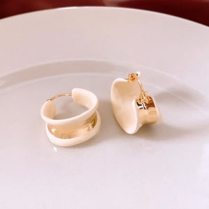 Detail of 18k gold plated hoop earrings with creamy white enamel on a white ceramic tray