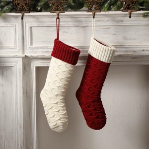 Pair of large red and white knitted Christmas stockings with fish scale pattern texture