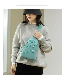 Close-up of mint green nylon crossbody bag showing dual parallel zipper front pockets