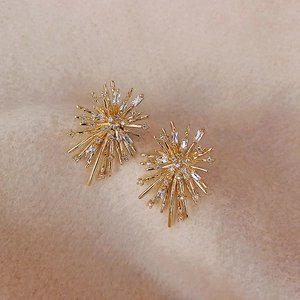 Elegant gold fireworks tassel earrings with sparkling crystals on beige fabric