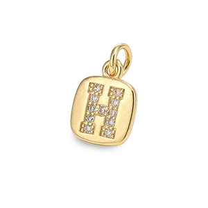 Macro detail of a gold square pendant featuring a cubic zirconia inlaid letter H design