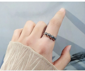 Macro view of a silver spinning ring with five rotating beads on an adjustable band