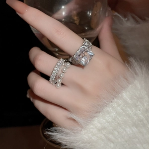Détails des bagues en argent avec zircon carré et accents élégants de perles sur les doigts