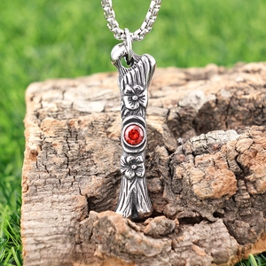 Vintage stainless steel necklace with red gemstone and floral engraving on wood