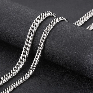 Macro shot of silver titanium steel Cuban link chains on a textured black stand