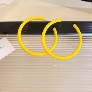Macro shot of minimalist yellow geometric hoop earrings with a matte lacquer finish