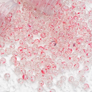 Macro shot of transparent glass beads with red swirl patterns for jewelry making