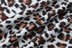Gros plan sur la texture du tissu à imprimé léopard noir et marron sur fond blanc