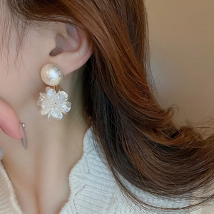 Détail de boucles d'oreilles fleurs élégantes avec perles portées par un mannequin
