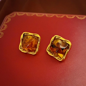 Macro detail of vintage square amber resin earrings with twisted gold metal frames