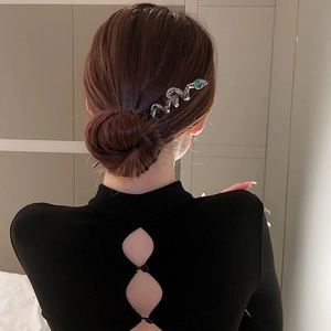 Detail shot of a silver snake hair pin with green eyes on a model's elegant bun