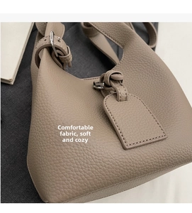 Détail du sac seau en cuir taupe avec texture grainée et boucle argentée ajustable