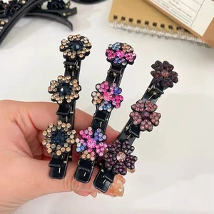 Dettaglio di tre fermagli neri per capelli con strass scintillanti oro, rosa e viola