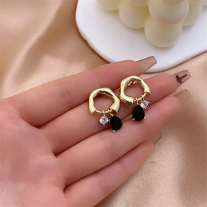 Detail of Christmas earrings featuring gold textured hoops with black teardrop pendants