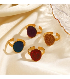Close-up of four vintage oval enamel rings in purple, blue, and glitter on gold band