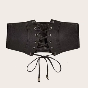 Détail d'une ceinture corset vintage noire avec laçage croisé et œillets en métal argenté