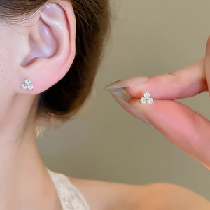 Close-up of elegant gold clover earrings with sparkling white stones on ear model