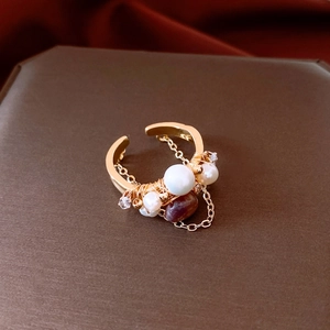 Detailed macro view of 18k gold-plated ring with pearls, red stone, and hanging chain