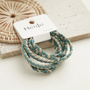 Detailed close-up of blue and beige twisted elastic hair ties on natural straw mat