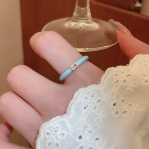 Macro detail of sky blue resin flower ring with golden base on a warm wood background